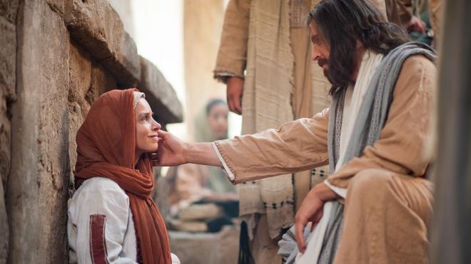 Jesus heals a woman by touching her face.