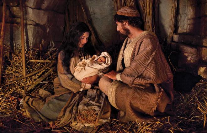 Joseph and Mary in a barn. Mary is holding baby Jesus.